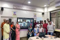 Alumni Connect participants gathered for a photo with online attendees on screen