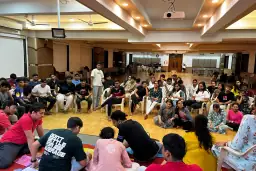 Alumni gathered in a circle indoors during the night-over